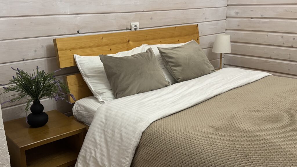 Затишна спальня у теплих тонах беж-капучино. Для вашого комфортного сну — постіль із натурального сатину та м’яке велюрове покривало. Естетичне дерев’яне узголів’я ліжка, приліжкові тумби з декором та м’яке освітлення створюють атмосферу спокою.