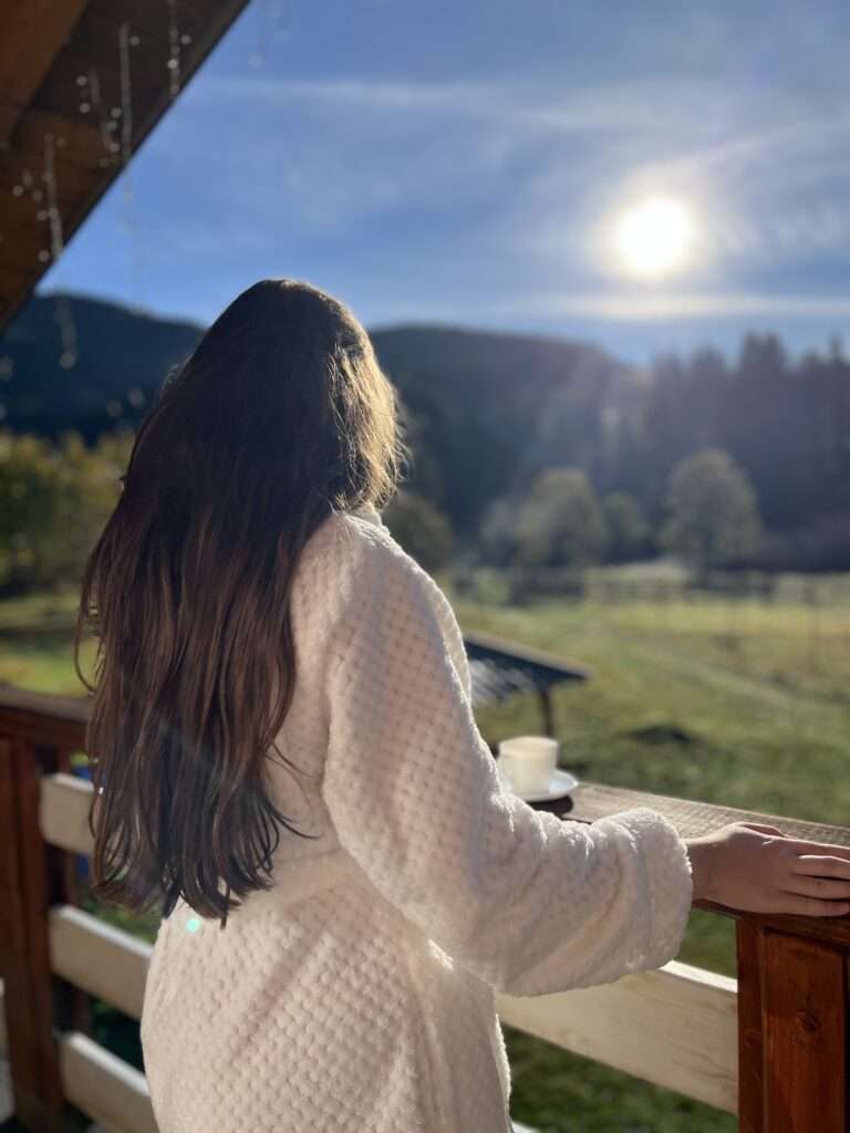 Тераса на другому поверсі. Дівчина стоїть та милується карпатським світанком.