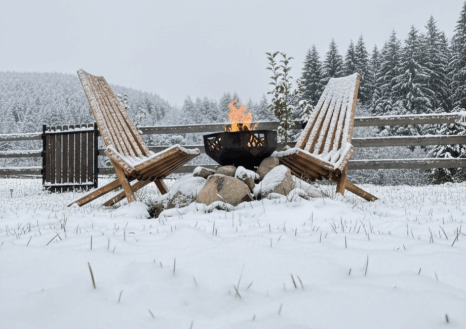 Вогонь у чаші та крісла Кентуккі, засипані снігом, у дворі Маєтку Діда.